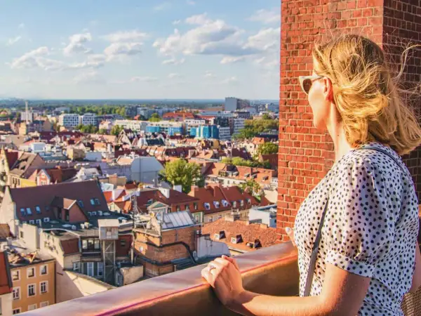 Kobieta podziwia panoramę Wrocławia, planując, co zobaczyć w 1 dzień. Widok na dachy kamienic i niebo.