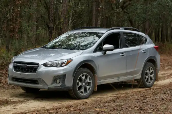 Srebrny Subaru Crosstrek na leśnej drodze, gotowy na przygodę.