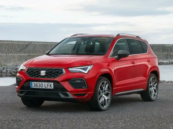 Czerwony Seat Ateca na tle kamiennego nabrzeża. Wiele osób szuka seat ateca opinie przed zakupem.