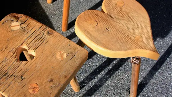 Drewniane taborety do kuchni, jeden w kształcie serca, drugi kwadratowy z wycięciem w kształcie serca.