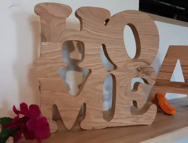 Grosse lettre en bois formant le mot "HOME", décorée de fleurs et d'une petite décoration orange.