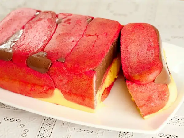 Zuppa inglese ricetta originale emiliana: strati di pan di spagna rosa, crema pasticcera gialla e cioccolato, decorata con savoiardi rossi e gocce di cioccolato.