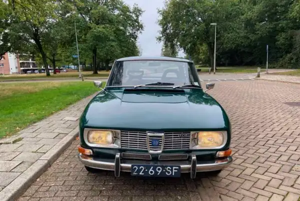 En grön Saab 99 står parkerad på en tegelstensbelagd uppfart, redo för en tur genom svenska landskap.