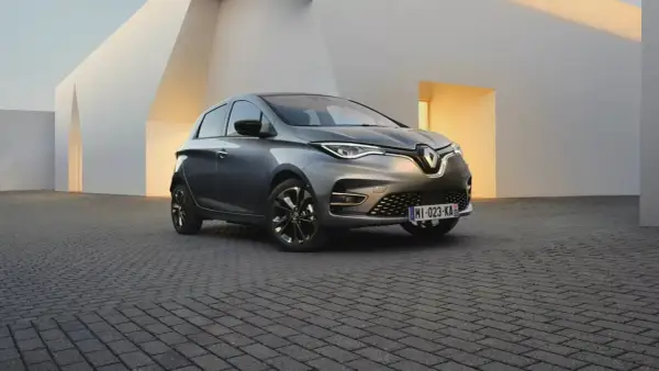 Une Renault Zoe grise, symbole de la mobilité électrique et de son autonomie, se gare devant une architecture moderne aux lignes épurées.