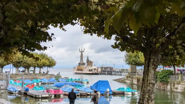 Bunte Tretboote liegen am Steg, im Hintergrund die Imperia-Statue und ein Dampfer am St. Galler See.