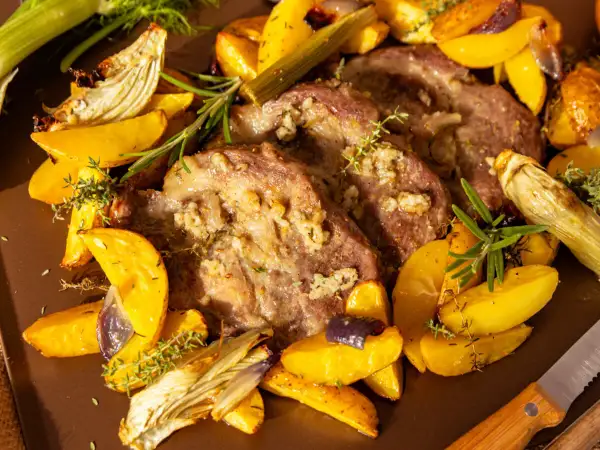 Saftiges Schweinesteak im Backofen ohne Anbraten, umgeben von goldbraunen Kartoffelspalten, Fenchel und Kräutern.