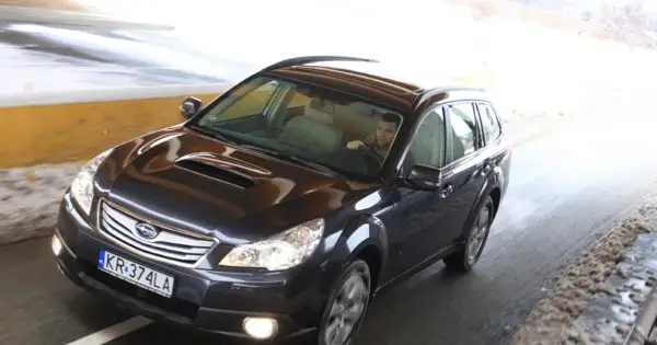 Ciemny Subaru Outback 2025 jedzie przez tunel, kierowca w szaliku.