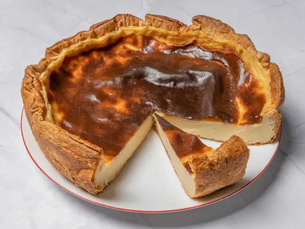 Une délicieuse tarte au flan, dorée et légèrement caramélisée, avec une part coupée pour révéler sa texture crémeuse.
