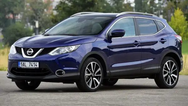 Granatowy Nissan Qashqai 2016 z chromowanymi relingami dachowymi i felgami.