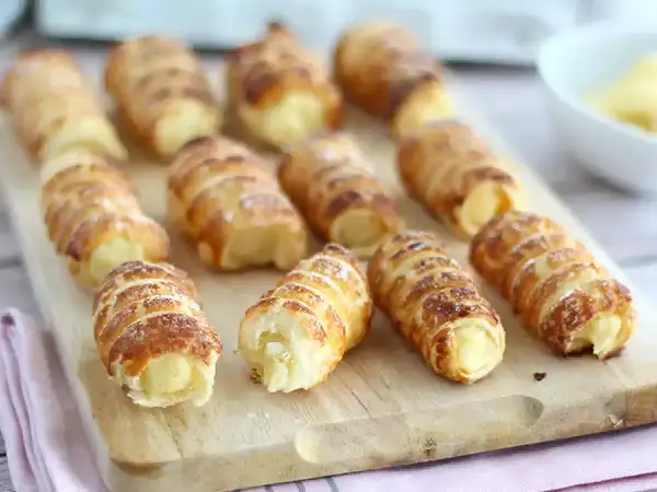 Krämiga bakelser, som italienskt godis, ligger på en träskärbräda.