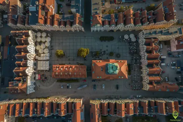 Widok z lotu ptaka na rynek w Jeleniej Górze. Widać kolorowe kamienice, kawiarniane ogródki i zabytkowy ratusz. To świetne miejsce na odkrywanie jeleniogórskich atrakcji.