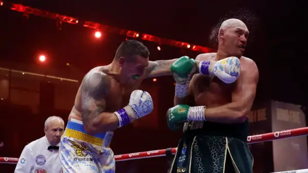 Boxer lands a punch as the referee watches. This intense moment captures the action, and in boxing, "UD" means a unanimous decision win.
