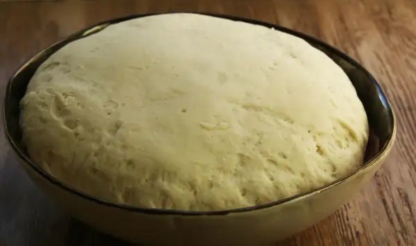 Puszyste ciasto na pizzę wyrosło w misce, gotowe do dalszej obróbki.
