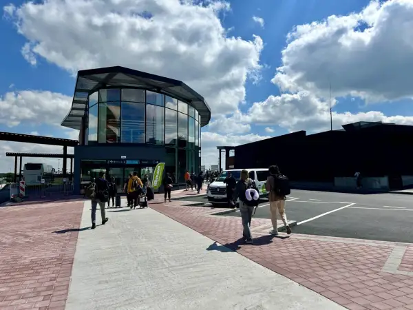 Ludzie z bagażami wchodzą do nowoczesnego terminalu lotniska Bruksela-Charleroi.