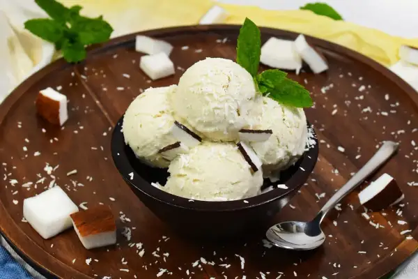 Schüssel mit cremigem Kokoseis, garniert mit Kokosraspeln und Minze. Perfekt, um Kokoseis selber zu machen!