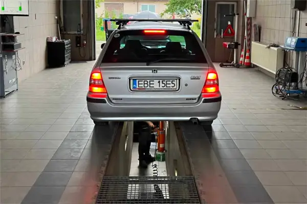 Srebrny Honda Civic na podnośniku w warsztacie. Tablica rejestracyjna EBE 15E5. Może poprzedni właściciel nie przerejestrował auta?