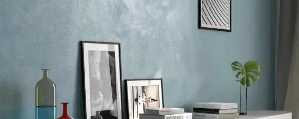 Parete con pittura effetto sabbiato azzurra, arricchita da quadri, vasi e libri. Ottime opinioni per questo stile.