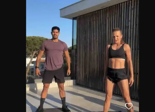 Anna Lewandowska i partnerka ćwiczą na tarasie. W tle drewniana ściana i drzewa.