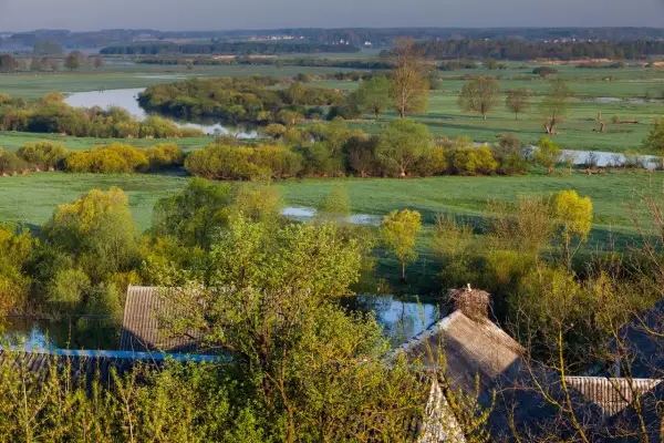 Podlasie samochodem: malownicze łąki, meandrująca rzeka i bocianie gniazdo na dachu. Idealne miejsce na spokojną podróż.