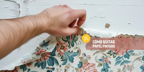 Mano retirando papel pintado floral de una pared blanca.