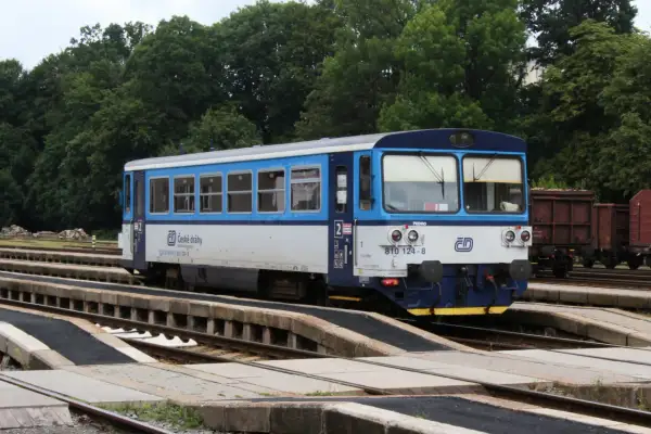 Niebiesko-biały pociąg České dráhy na torach, w tle drzewa. Może to być widok z granicy polsko czeskiej.