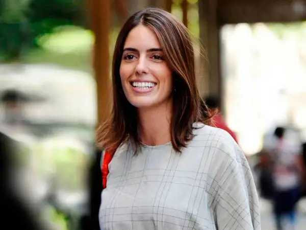 Sofía Palazuelo sonríe con su cabello castaño suelto y un vestido a cuadros.
