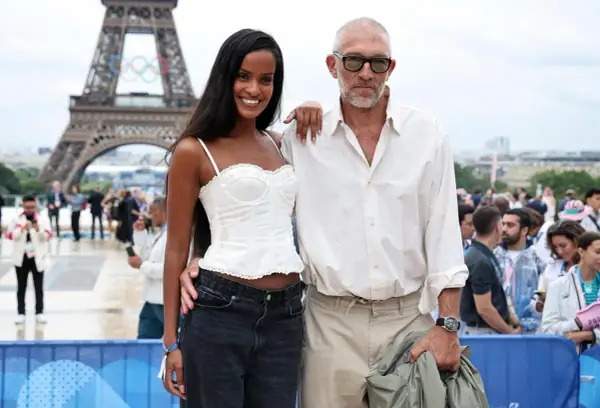 Narah Baptista sorride accanto a Vincent Cassel con la Torre Eiffel e gli anelli olimpici sullo sfondo.