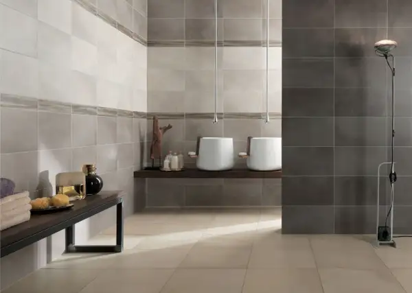 Bagno moderno con lavabi sospesi e piastrelle a diverse altezze, che creano un effetto visivo dinamico.