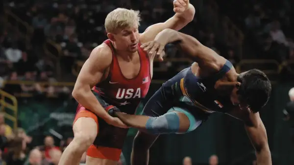 Två brottare i intensiv kamp. En bär USA:s färger, den andra en mörkblå dräkt. Spänningen är påtaglig i denna wrestling sverige-match.