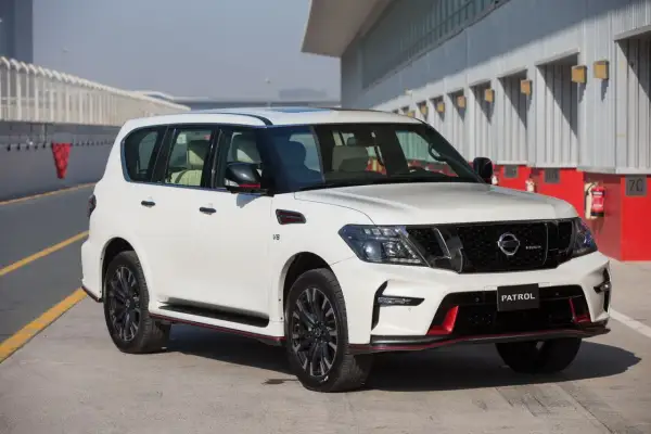 Biały Nissan Patrol Nismo z czerwonymi akcentami stoi na torze wyścigowym.