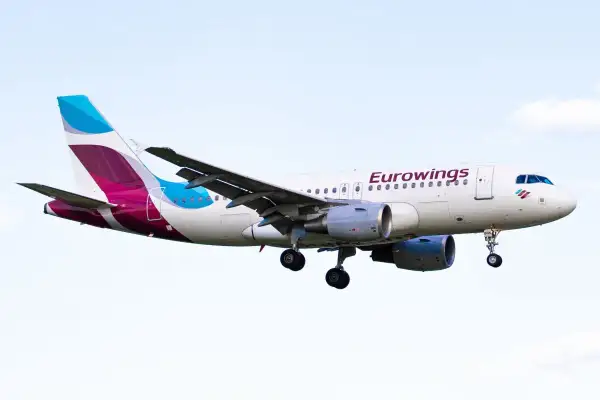 Samolot Eurowings z wysuniętym podwoziem na tle nieba.