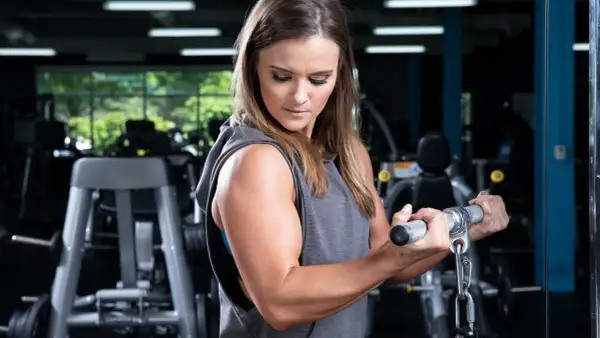 Woman performing bicep curls, demonstrating how to gain arm muscle at home for females.