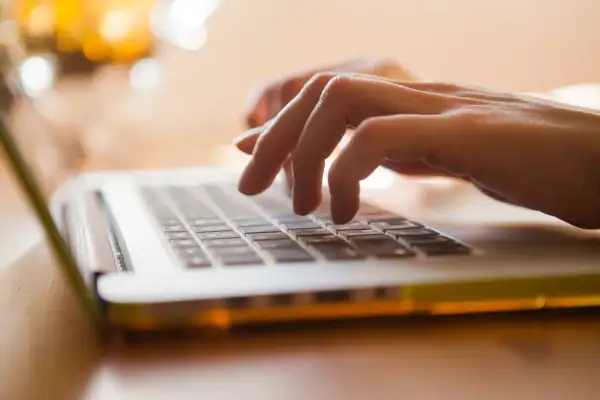 Mani che digitano su un laptop, con luci sfocate sullo sfondo. Un'istantanea del **mod ap 70** che cattura la concentrazione.