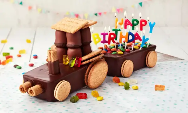 Schokoladen-Traktor-Torte, die man leicht selber machen kann, mit bunten Kerzen und Gummibärchen verziert.