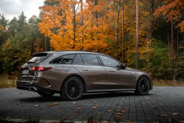 Elegancki Mercedes E300de kombi na tle jesiennego lasu.