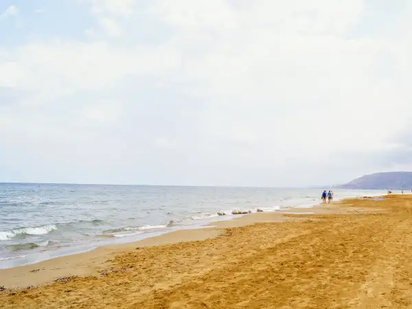Spokojne morze i piaszczysta plaża na Zakynthos w maju. Kilka osób spaceruje brzegiem, ciesząc się łagodnym słońcem i ciszą.