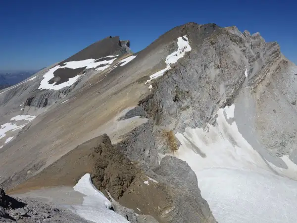 Vue spectaculaire d'une crête rocheuse et enneigée lors d'une barrhorn randonnée. Le ciel bleu azur domine.