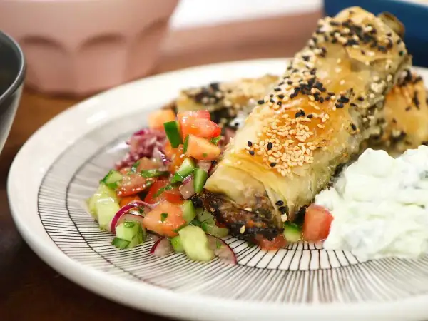 Krispiga filodegsrullar med sesamfrön, serverade med en fräsch tomatsallad och yoghurt. Ett utsökt burek recept!