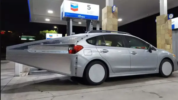 Silverbil med en stor, silverfärgad aerodynamisk förlängning bak. En uppfinning för att spara bensin vid en Chevron-mack.