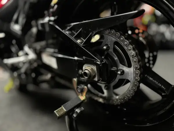 Zbliżenie na zębatkę i łańcuch motocyklowy. Dowiedz się, czym czyścić łańcuch motocyklowy, by był jak nowy.