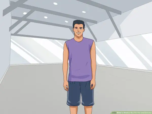 A man in athletic wear stands ready for shadow boxing in an empty gym.