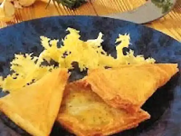 Délicieuse recette brick thon pomme de terre, croustillante et dorée, servie sur une assiette bleue avec une garniture jaune.