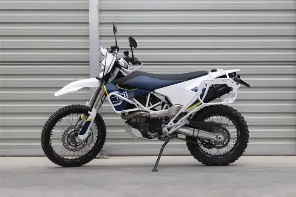 Motocykl enduro Husqvarna 701 z bagażnikiem i osłonami, biało-niebieski.