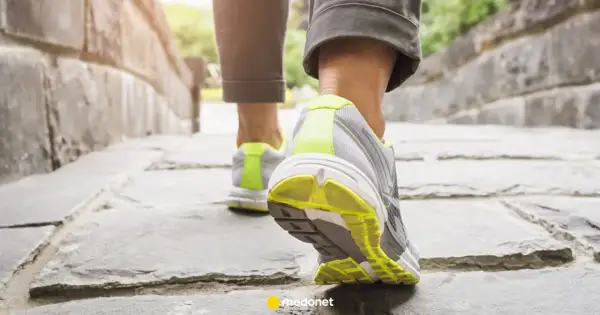 Zbliżenie na nogi w butach sportowych idące po kamiennej ścieżce.