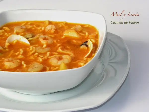 Cazuela de fideos con gambas y mejillones en un cuenco blanco.