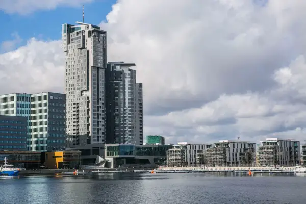 Nowoczesne sea towers w Gdyni, zdominowane przez szare i białe fasady, odbijają się w spokojnej wodzie portu.