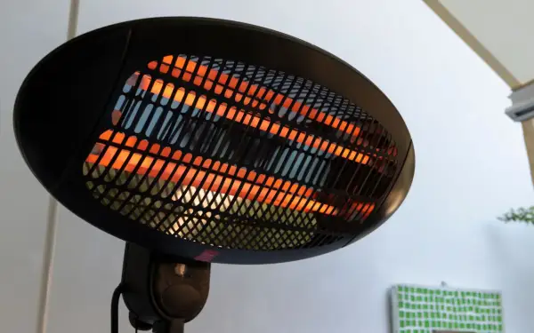 Lampada infrarossi terapia con elementi riscaldanti incandescenti arancioni dietro una griglia nera.