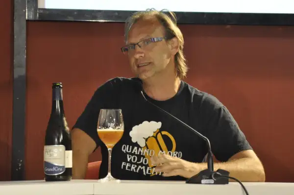 Uomo con bicchiere e bottiglia di birra artigianale, con maglietta che recita "Quando moro vojo fermentare". Non è birra industriale, ma passione!