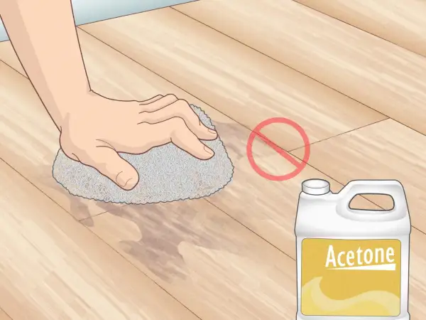 Main tenant, ne pas enlever peinture sur lino avec acétone. Une main frotte le sol avec une éponge.