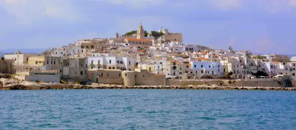 Un borgo bianco a picco sul mare, con un campanile in cima. Ricorda il vino primitivo, significato di sole e terra pugliese.